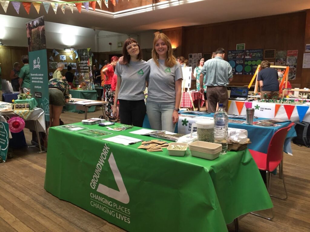 Laura stands with a colleague at an exhibition stand.