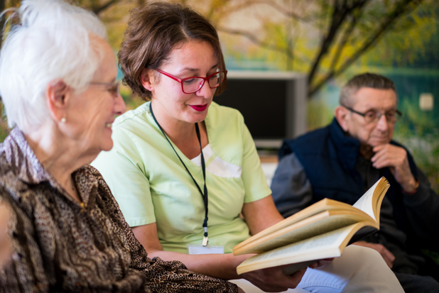 Volunteer assisting an senior lady by reading to her