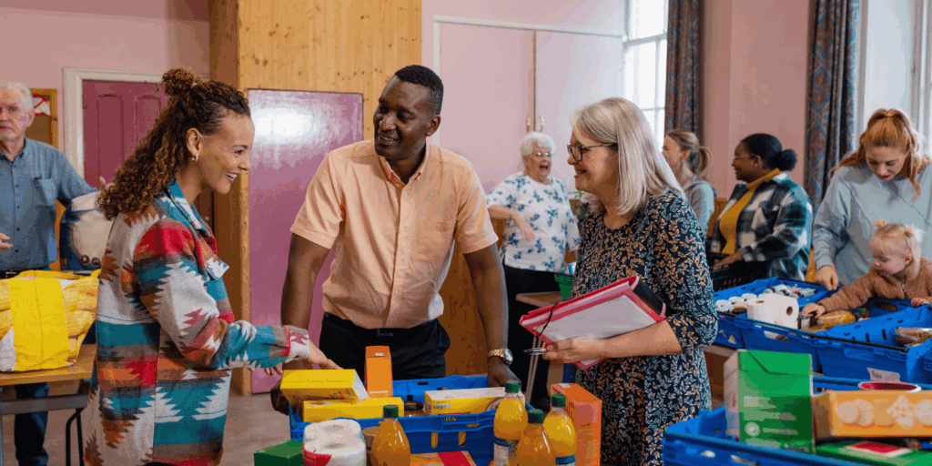 A group of people of mixed races crowded around a table, people of different ages are in the background