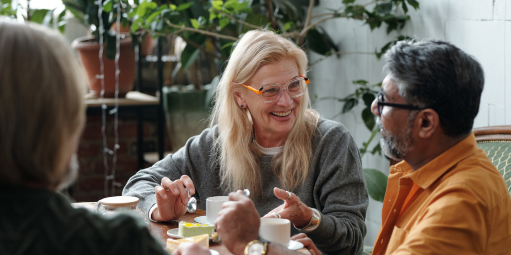 A woman sat on a table, in conversation with a man. Both are smiling